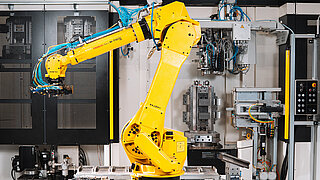 Roboter spannt Bauteile in Vorrichtung ein