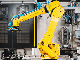 Roboter spannt Bauteile in Vorrichtung ein