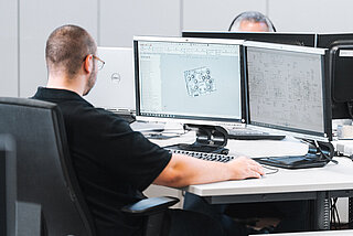 Mitarbeiter in der Konstruktionsabteilung arbeitet am PC mit CAD-Software