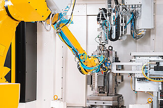 Roboter spannt Bauteile in Vorrichtung ein